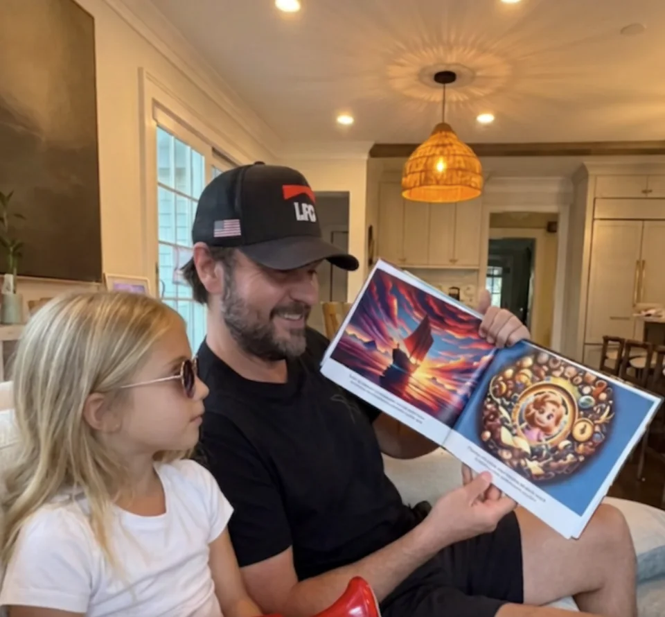 A dad reading a personalized storybook aloud to his daughter